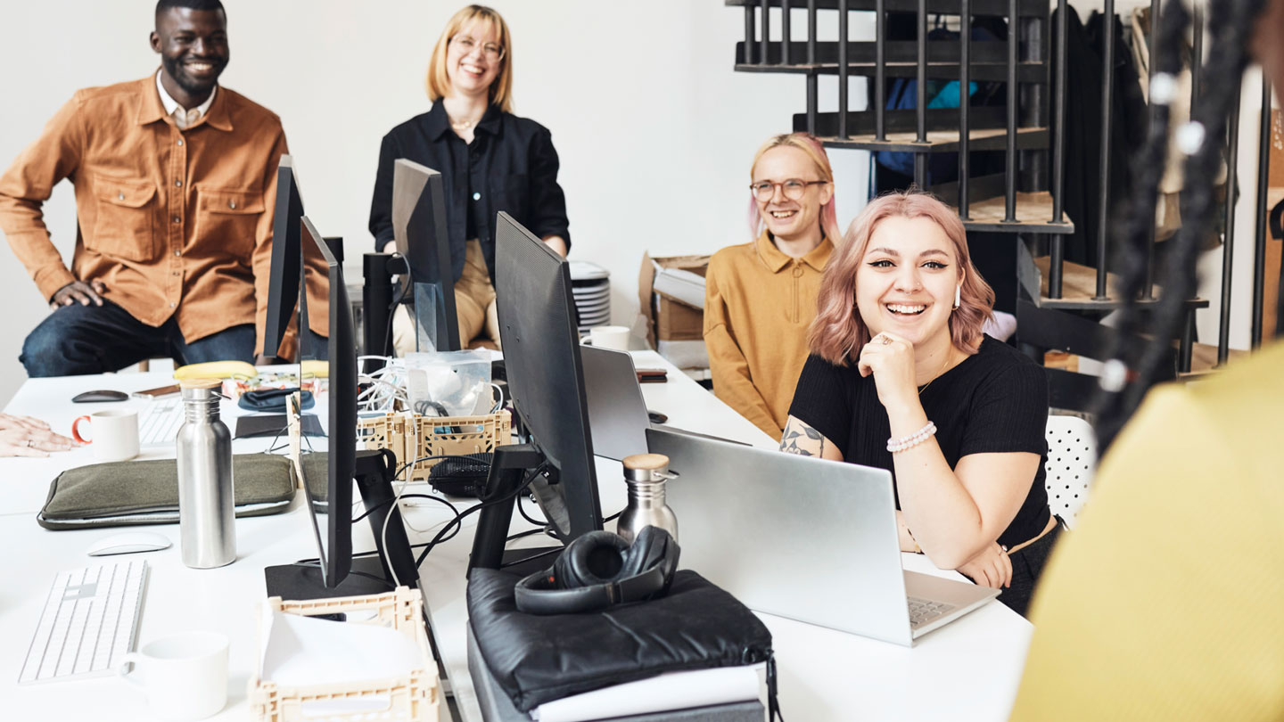 Group of people smiling around desk